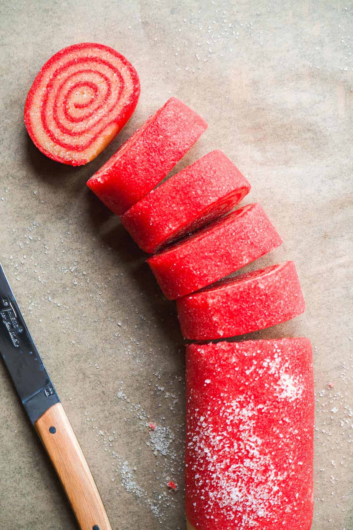 Peppermint swirl cookie dough sliced into cookies on parchment paper.