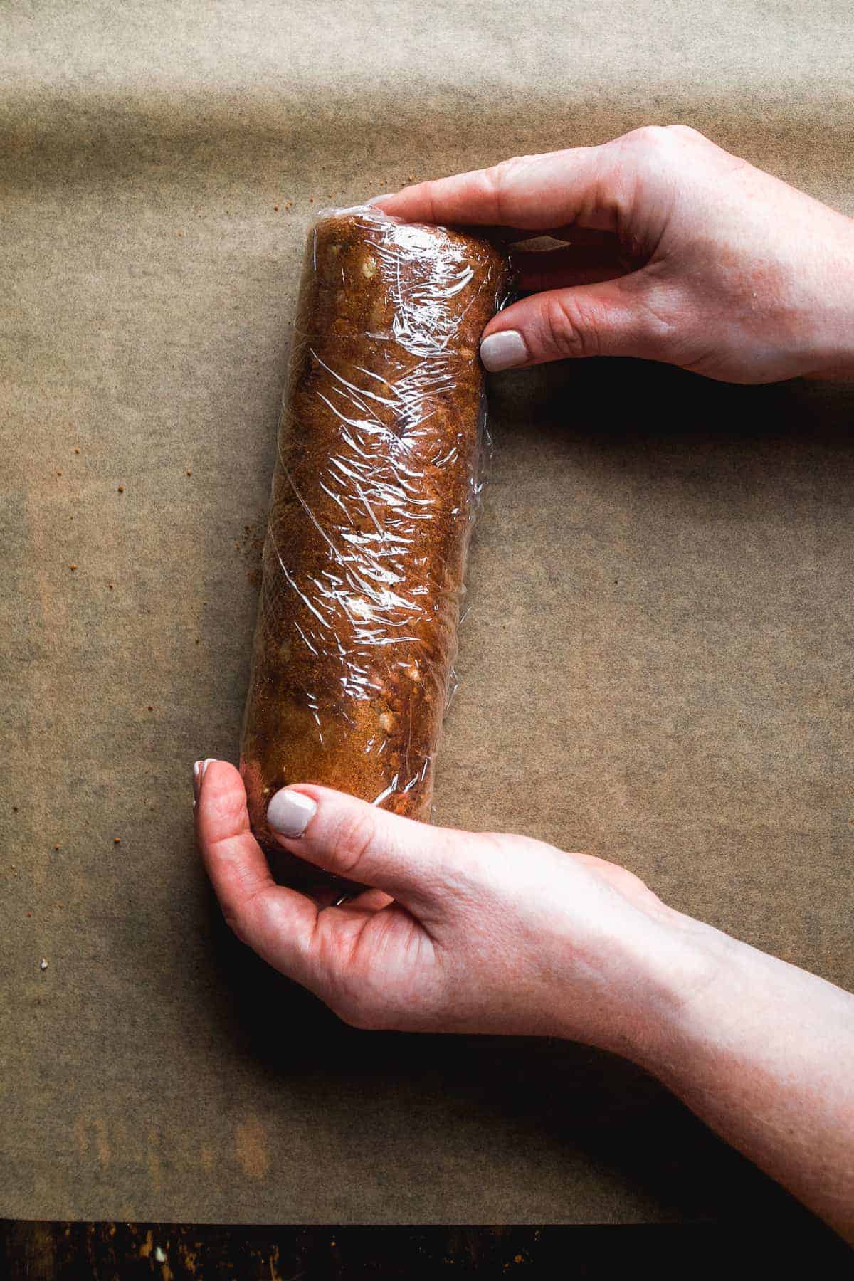 Cookie dough log wrapped in plastic wrap.