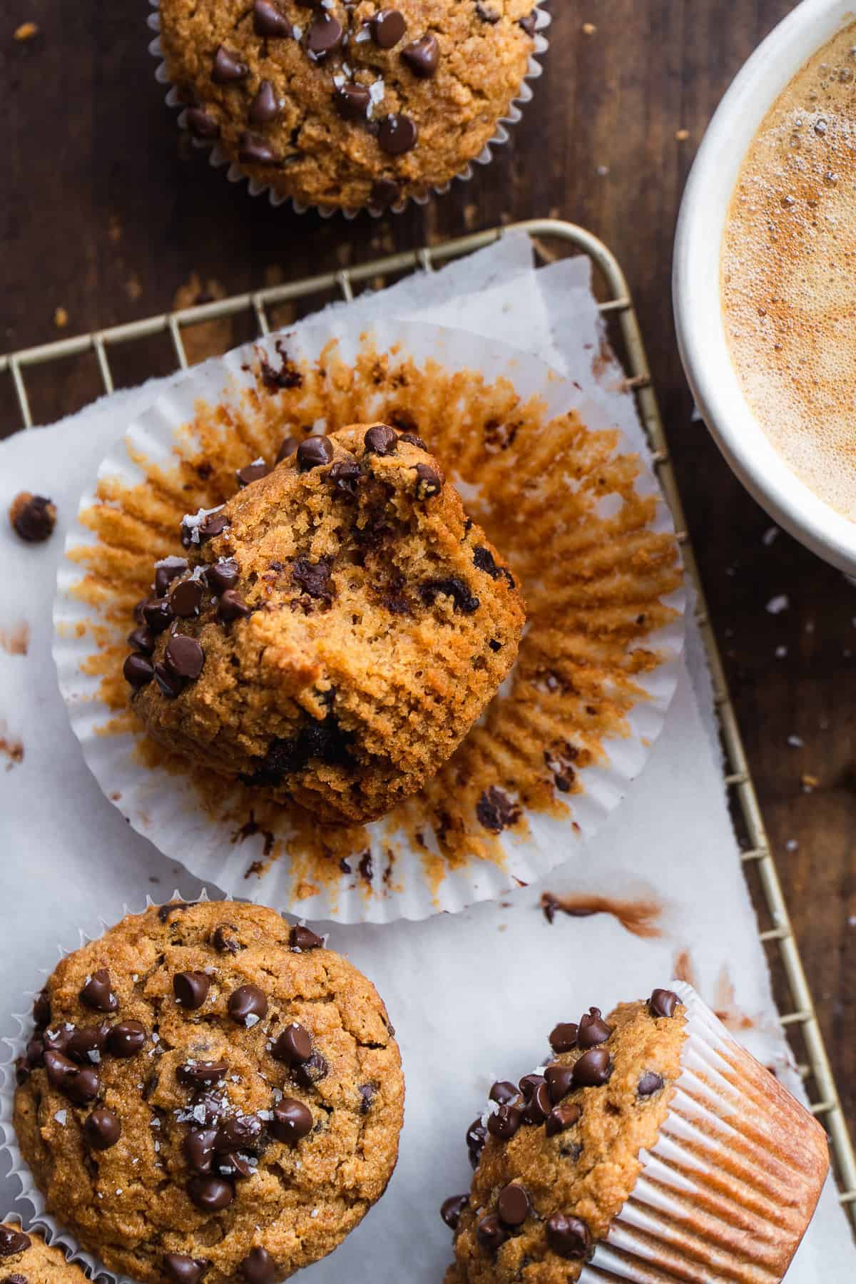 Paleo chocolate chip muffin with a bite taken out of it on a wire rack.