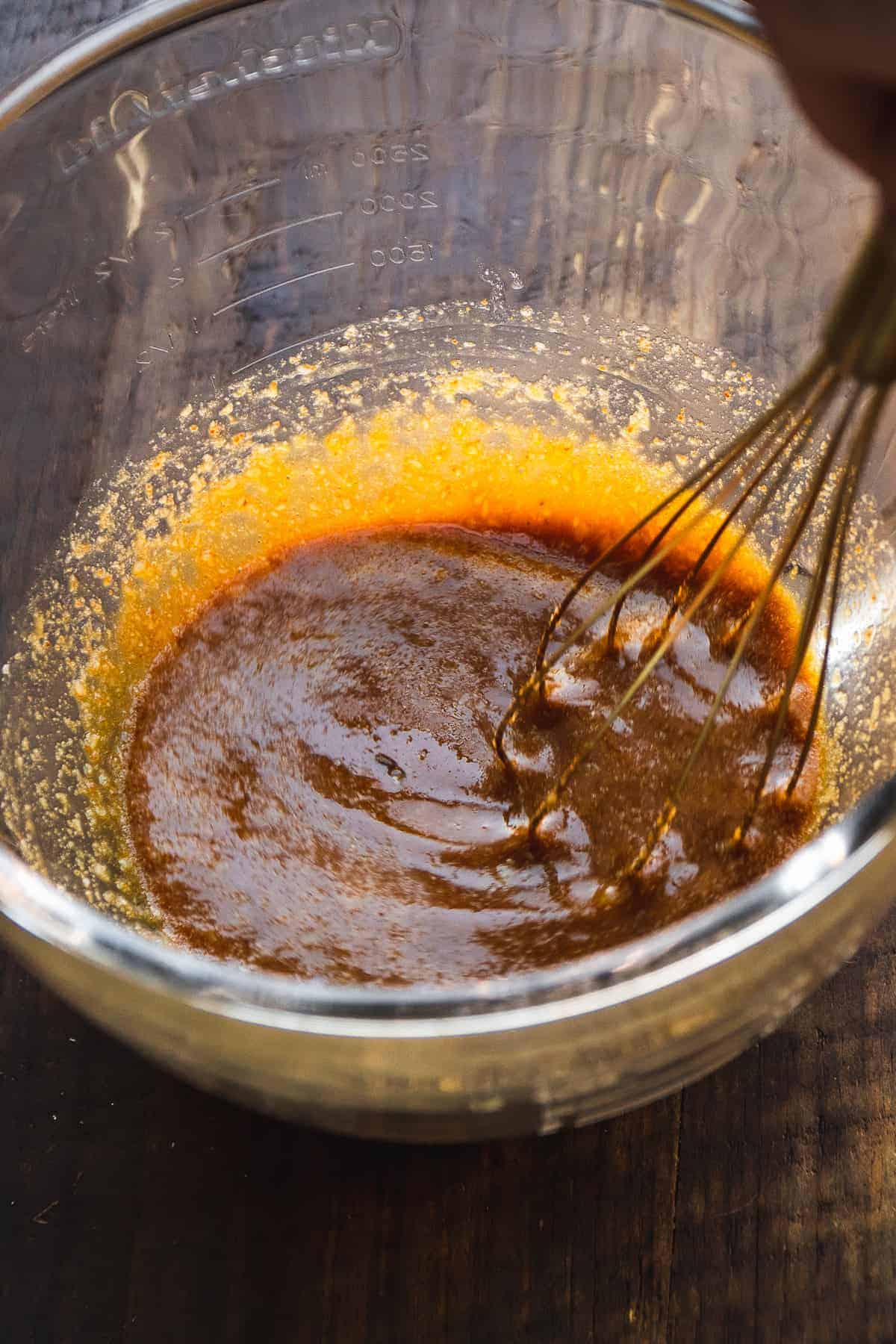 Person whisking wet ingredients in a bowl.