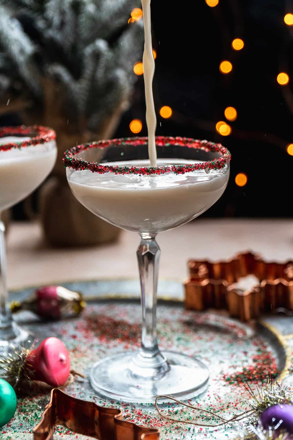 Sugar cookie martini being poured into a martini glass with a sprinkle rim.