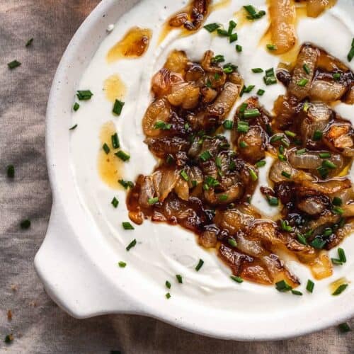 Overhead view of whipped goat cheese in a dish with caramelized onions.