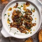 Overhead view of whipped goat cheese in a circular dish with onions.