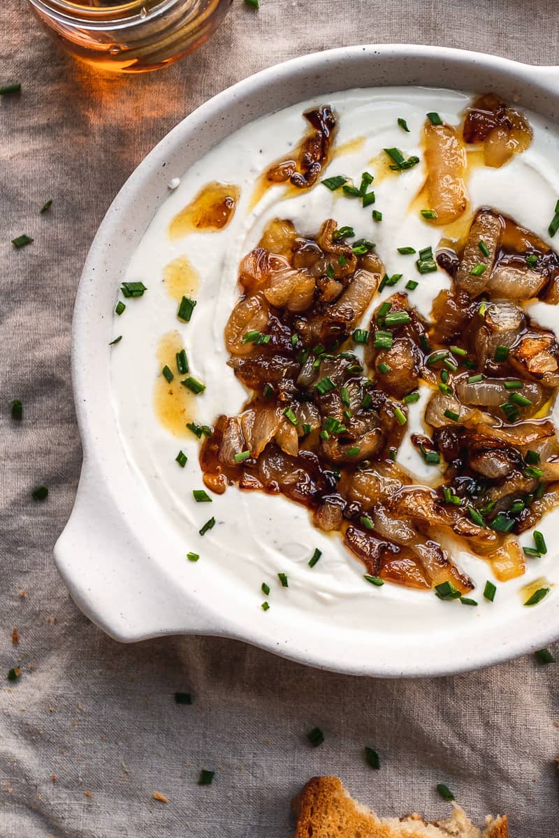 Overhead view of whipped goat cheese in a dish with caramelized onions.