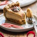 Slice of candy cane pie on a white plate with a fork taking a bite out of the pie.