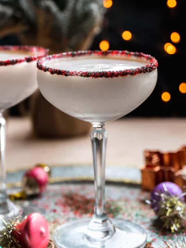 Sugar cookie martini on a silver platter with lights in the background.