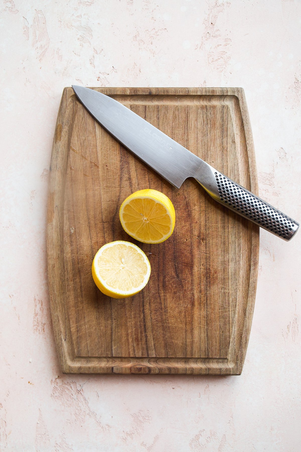 Lemon on  wooden cutting board cut in half.