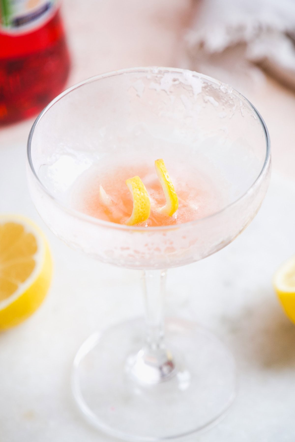 Empty cocktail glass with pink foam and a lemon twist.