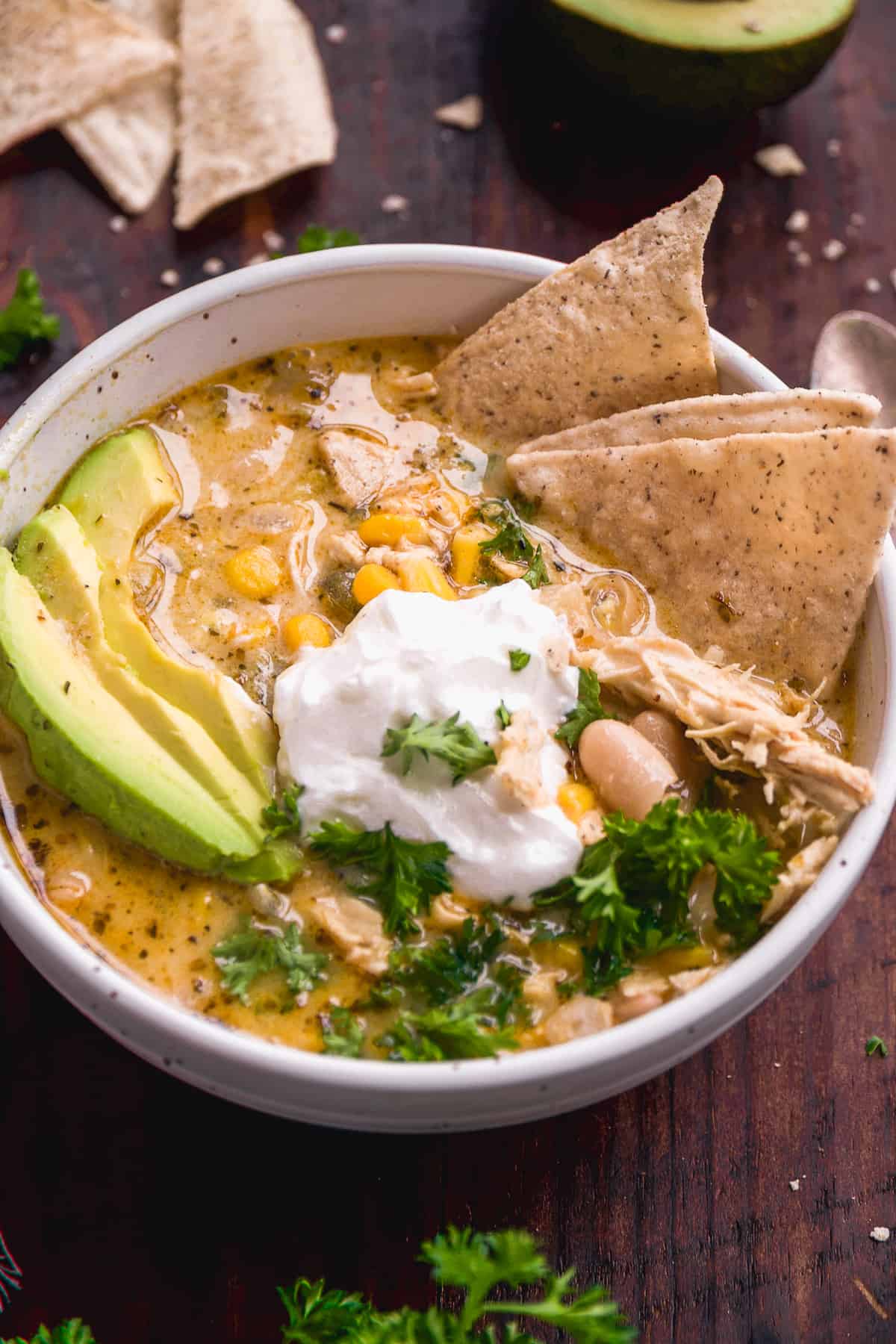 Bowl of chicken chili with chips and avocados.