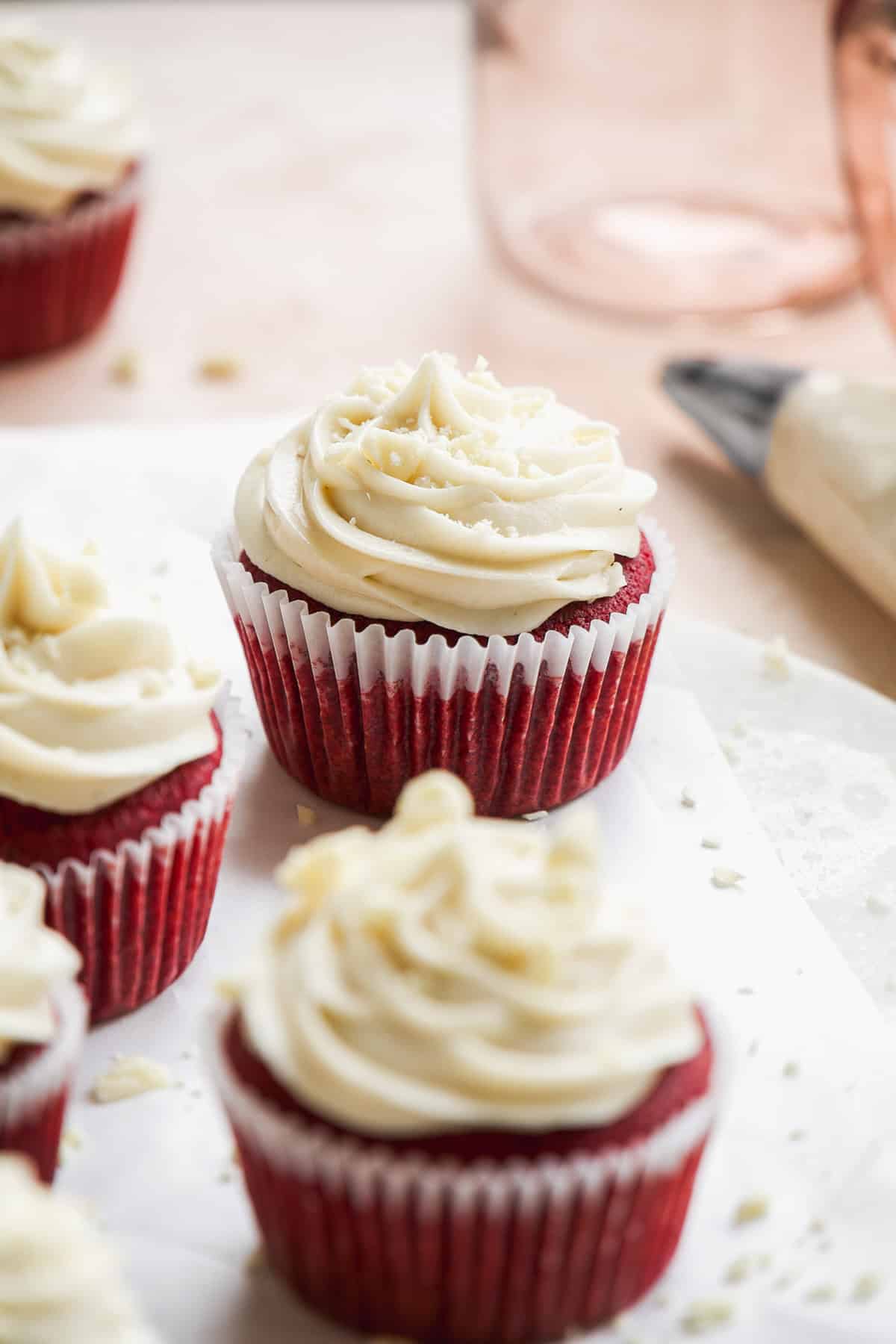 Side view of red velvet cupcakes with cream cheese frosting on top.