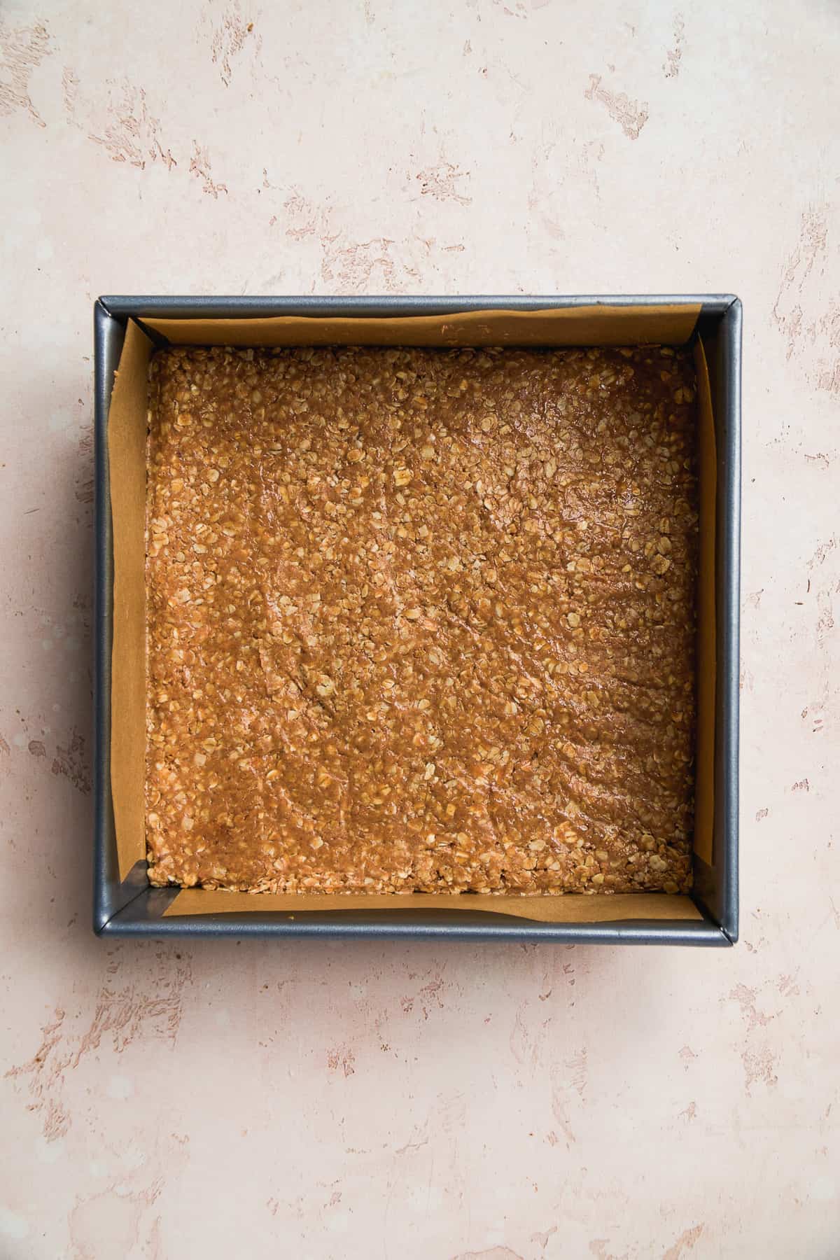 Square pan with peanut butter oats pressed into the pan.