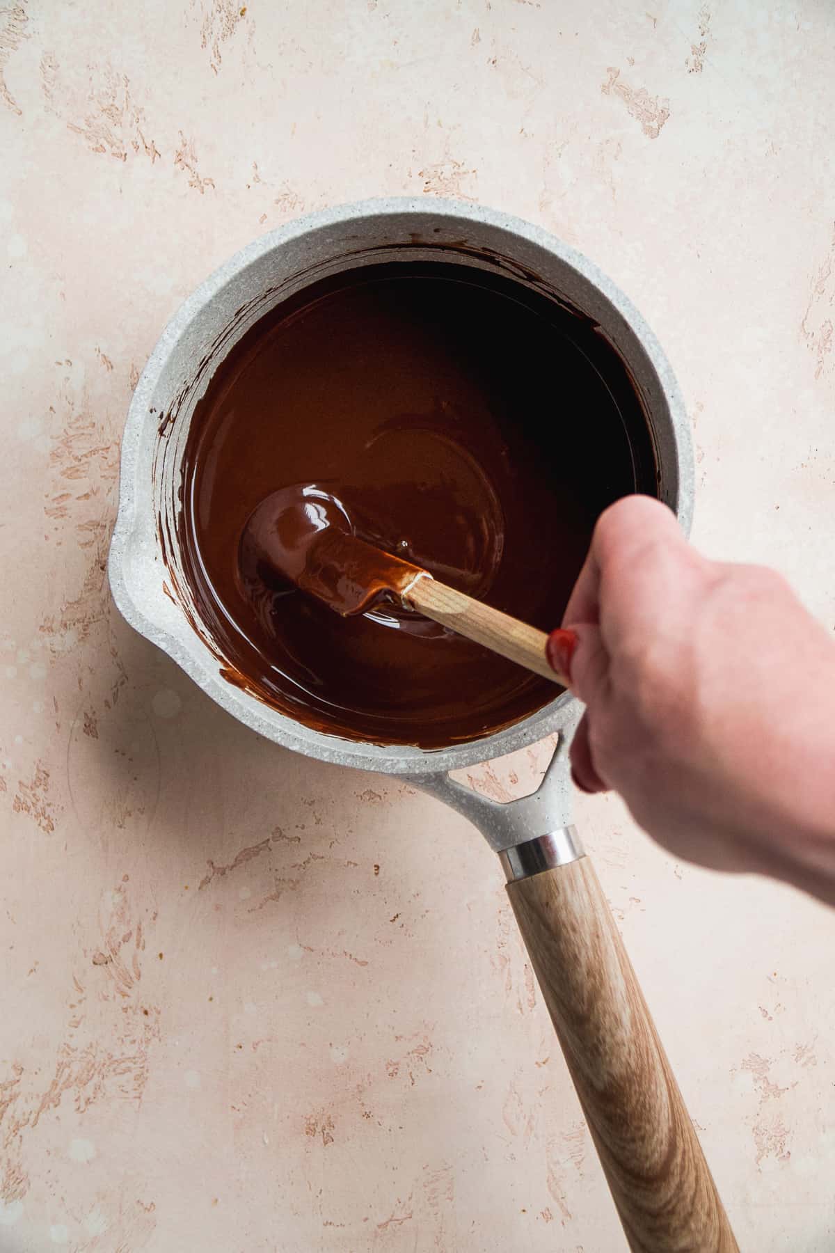 Person melting chocolate in a pot.