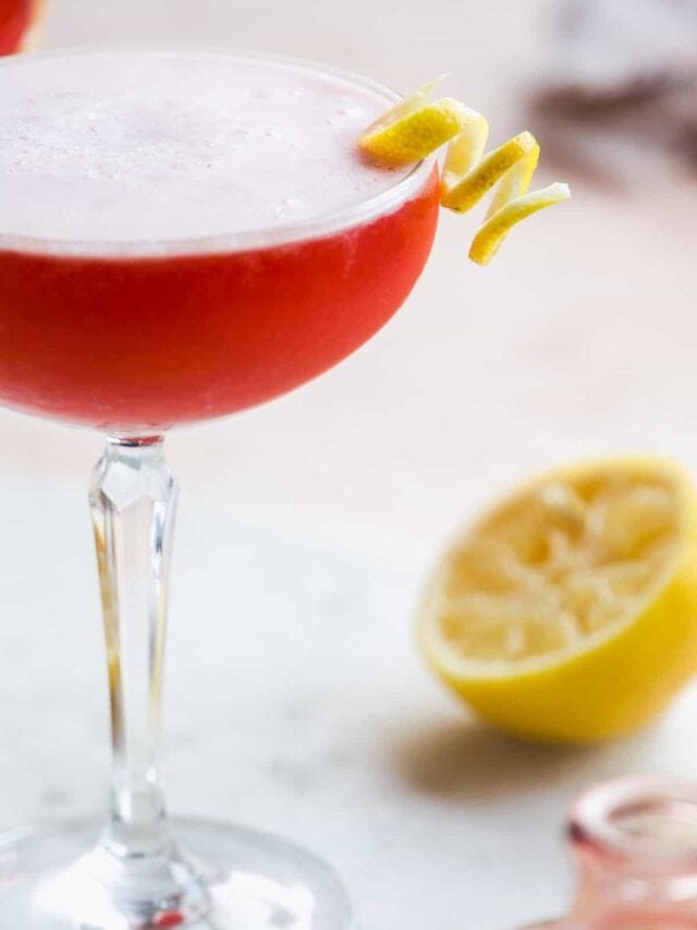 Aperol cocktail with lemon twist and froth on top.