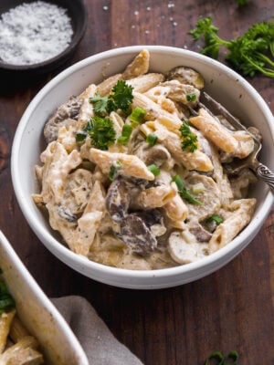 Bowl of baked goat cheese pasta on wooden surface.