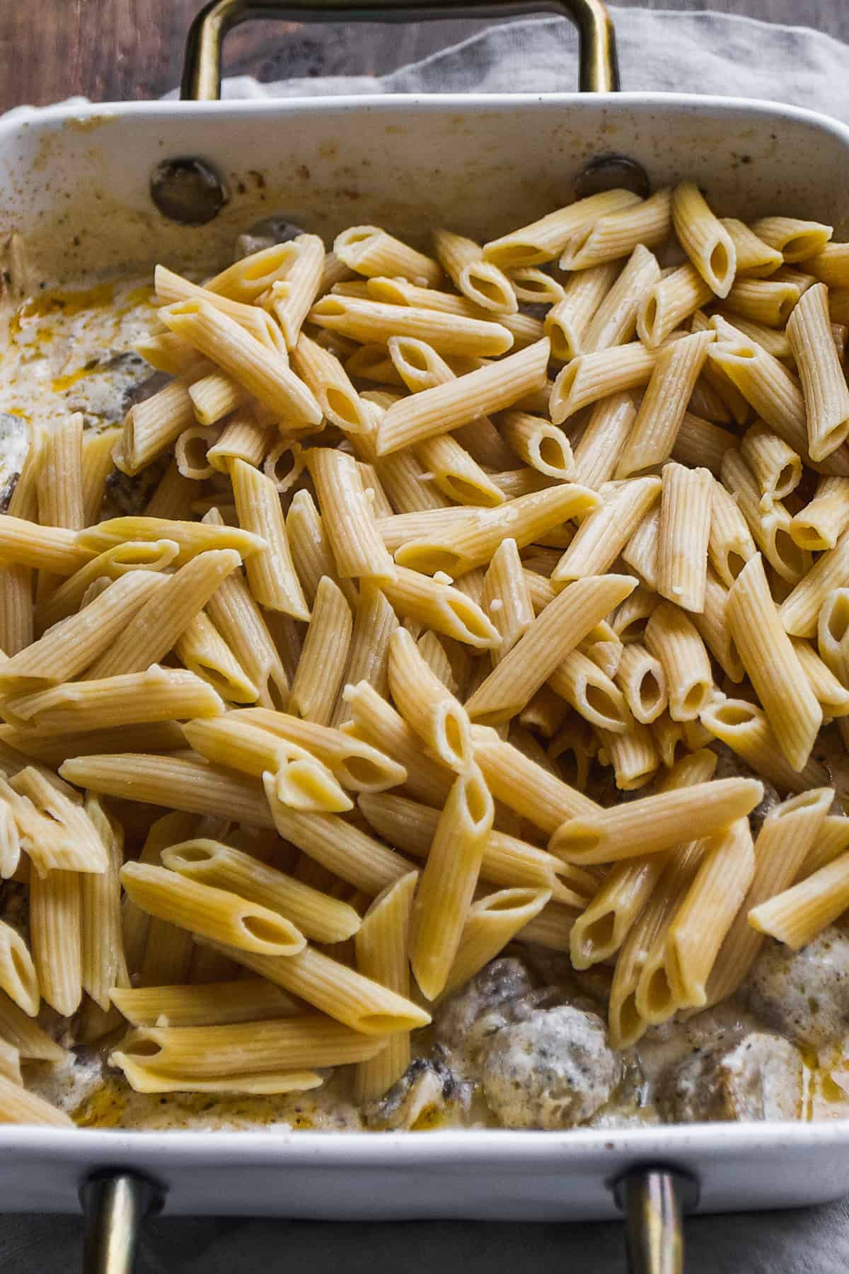 Pasta noodles about to mixed into baked goat cheese mixture.