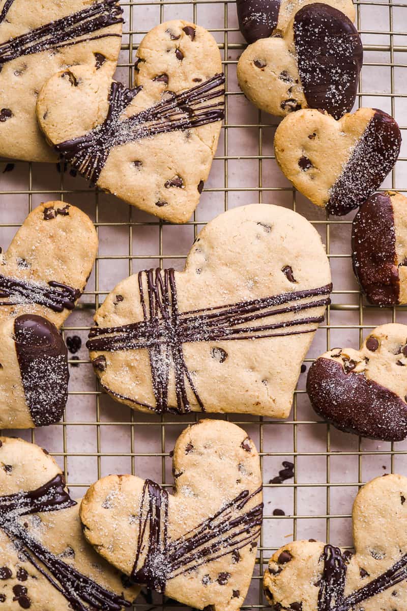 Chocolate chip cookies shaped like hearts on a wire rack.