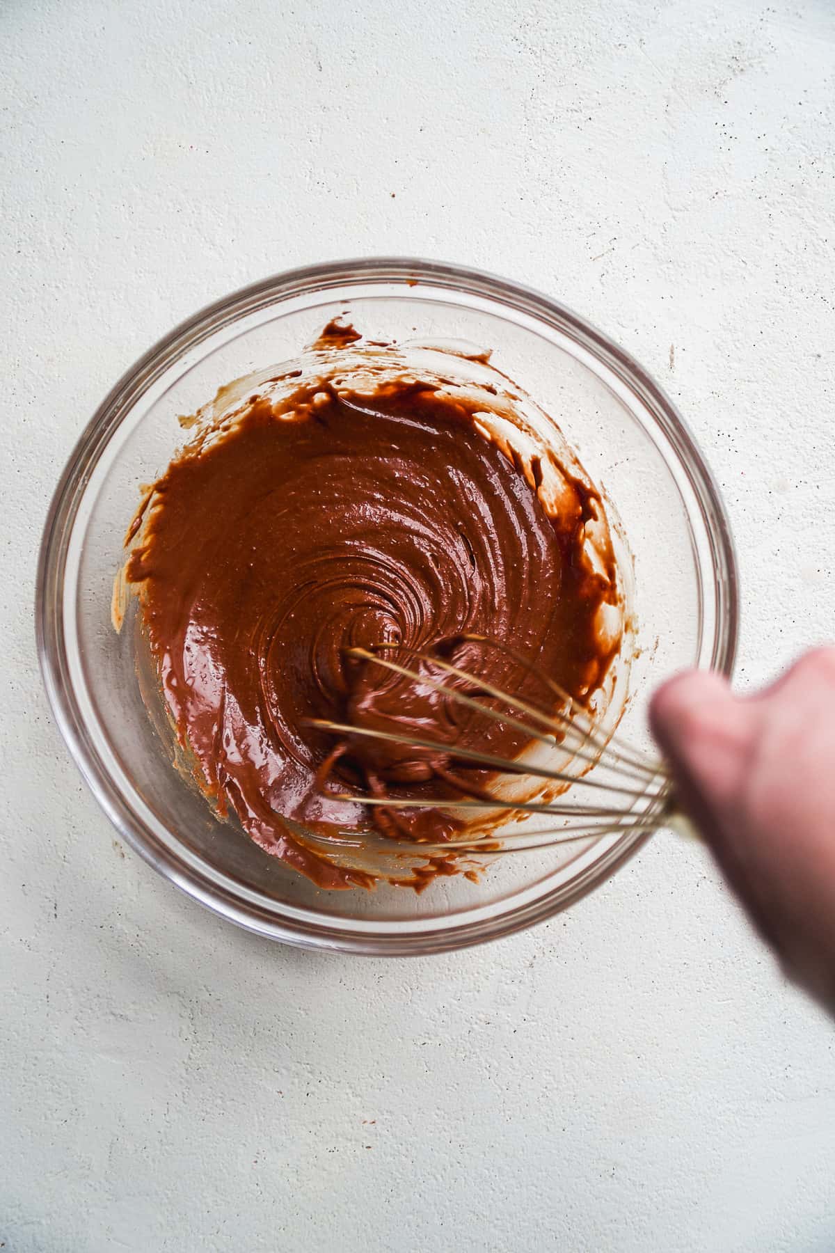 Person whisking chocolate into cookie batter.