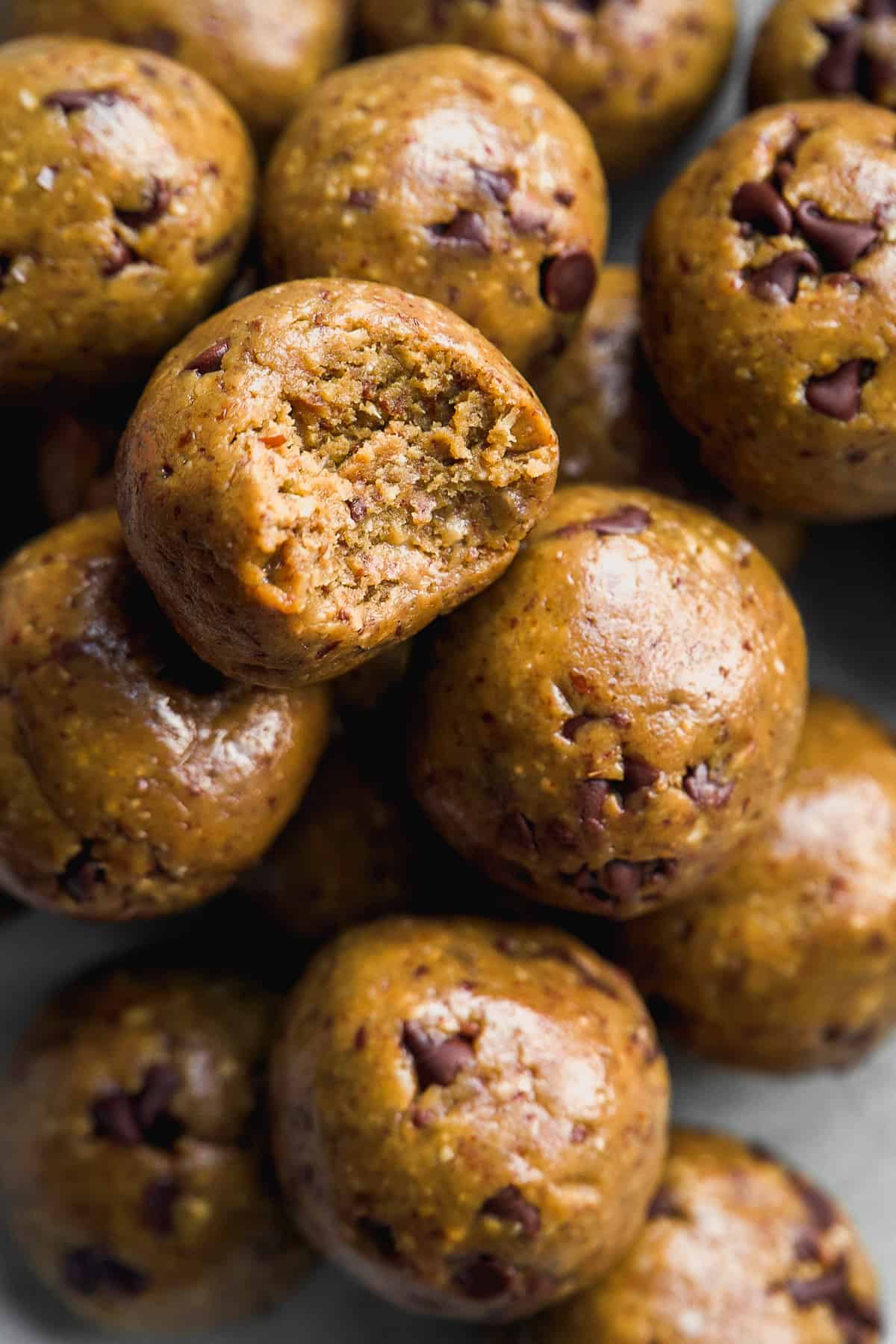 Cookie dough protein balls in a pile with a bite taken out of one.