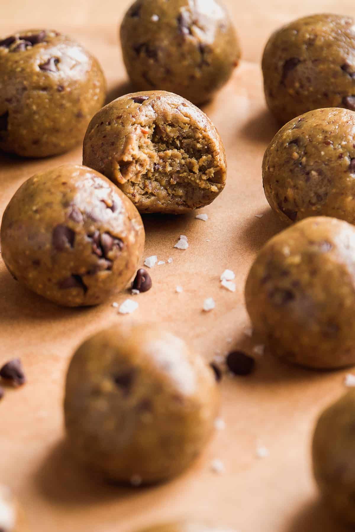 Cookie dough protein balls in parchment paper with a bite taken out of one.