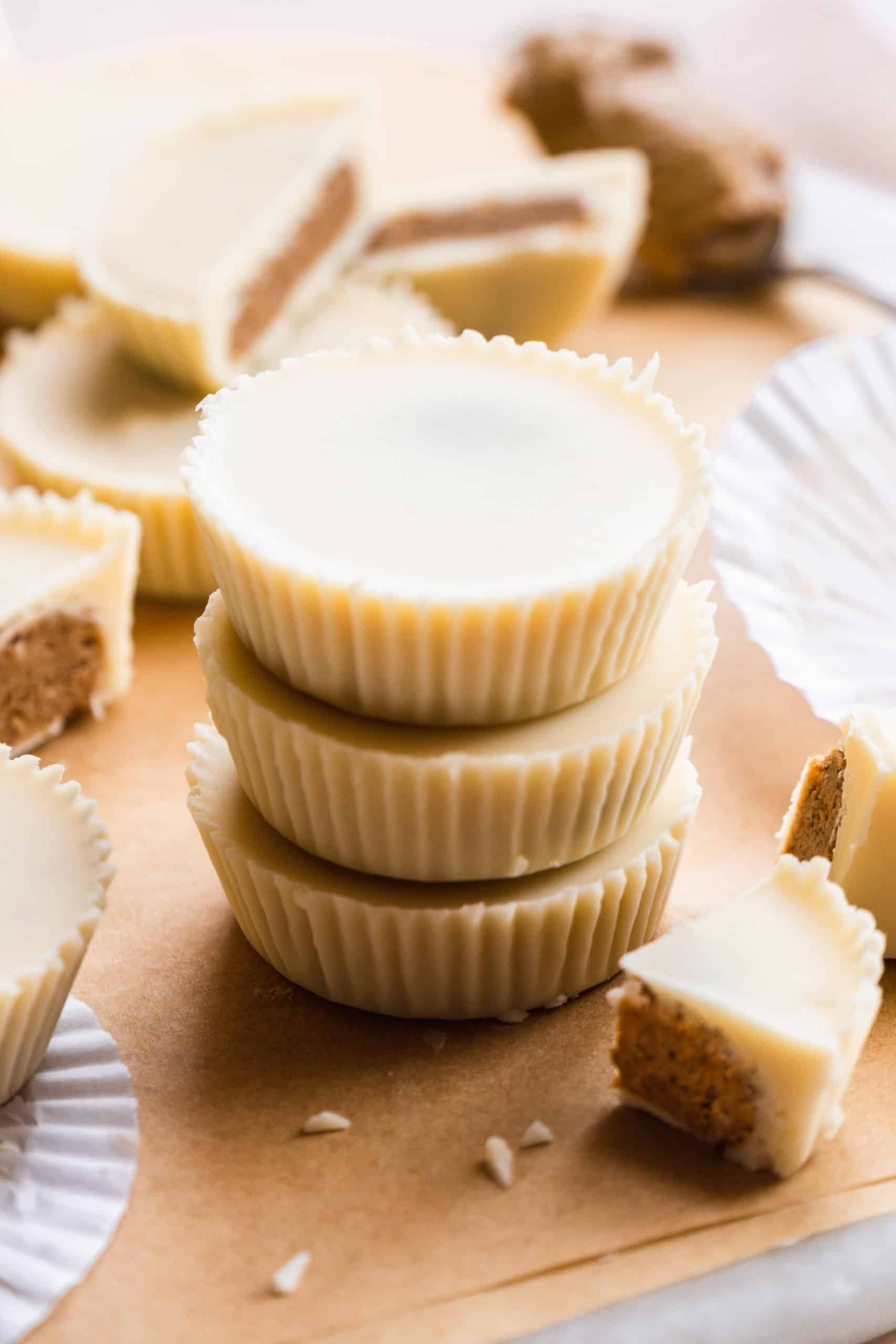 Stack of white chocolate peanut butter cups on parchment paper.