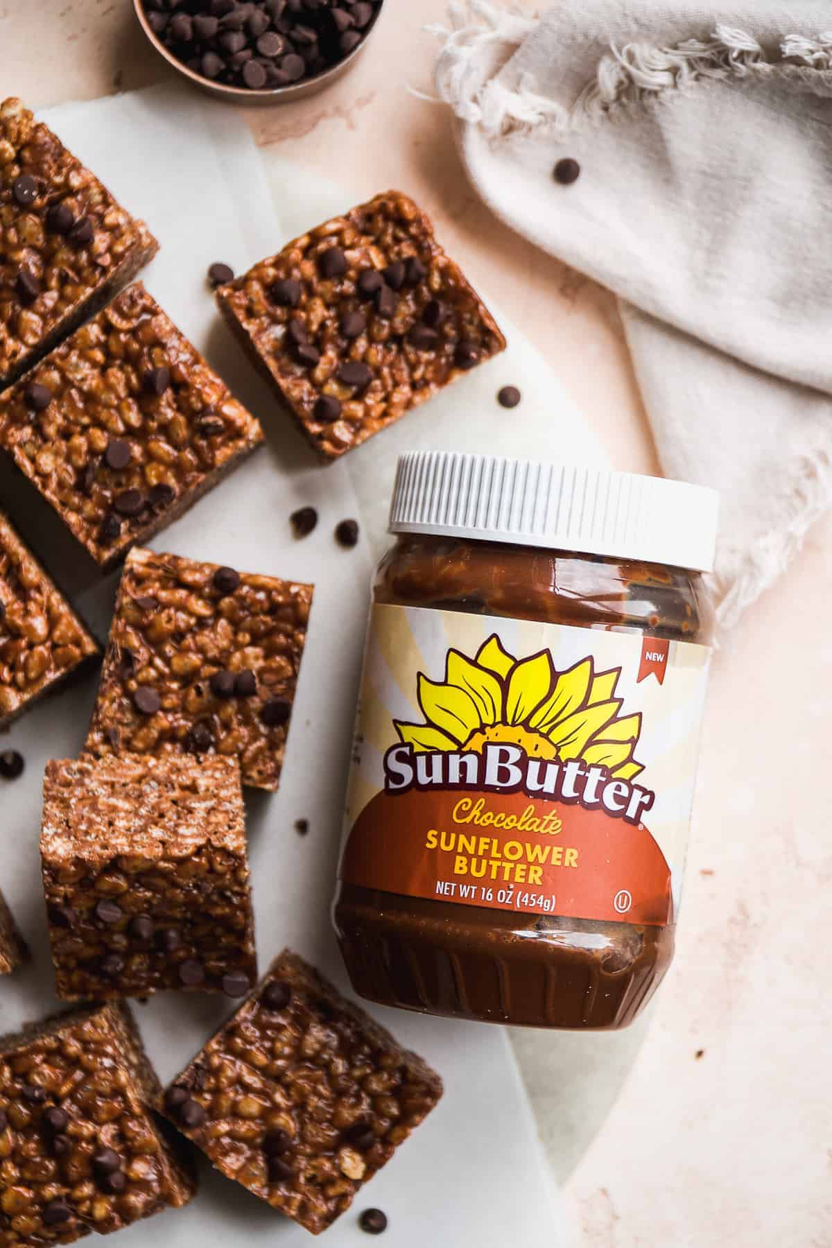 A jar of chocolate sunflower butter with rice krispie treats next to it.