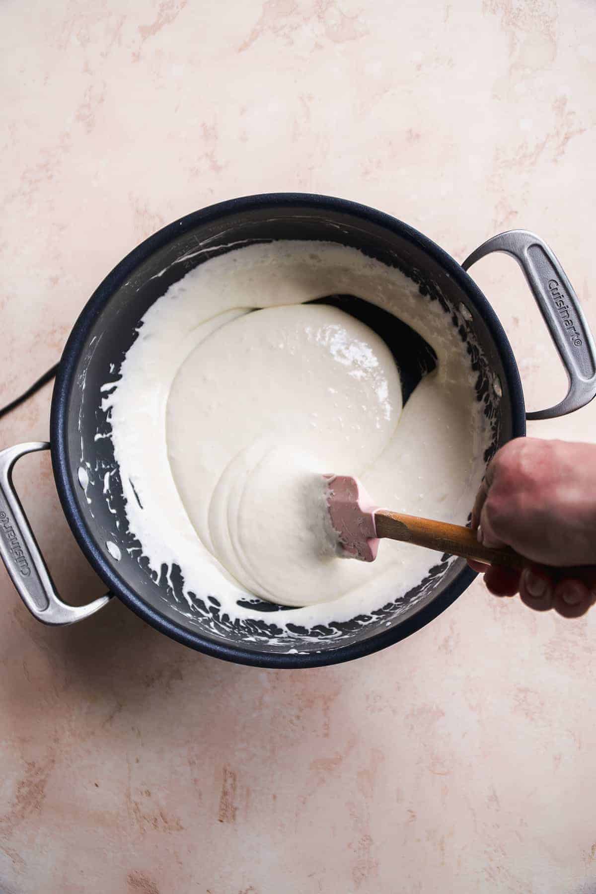 Person stirring melted marshmallows in a large pot.