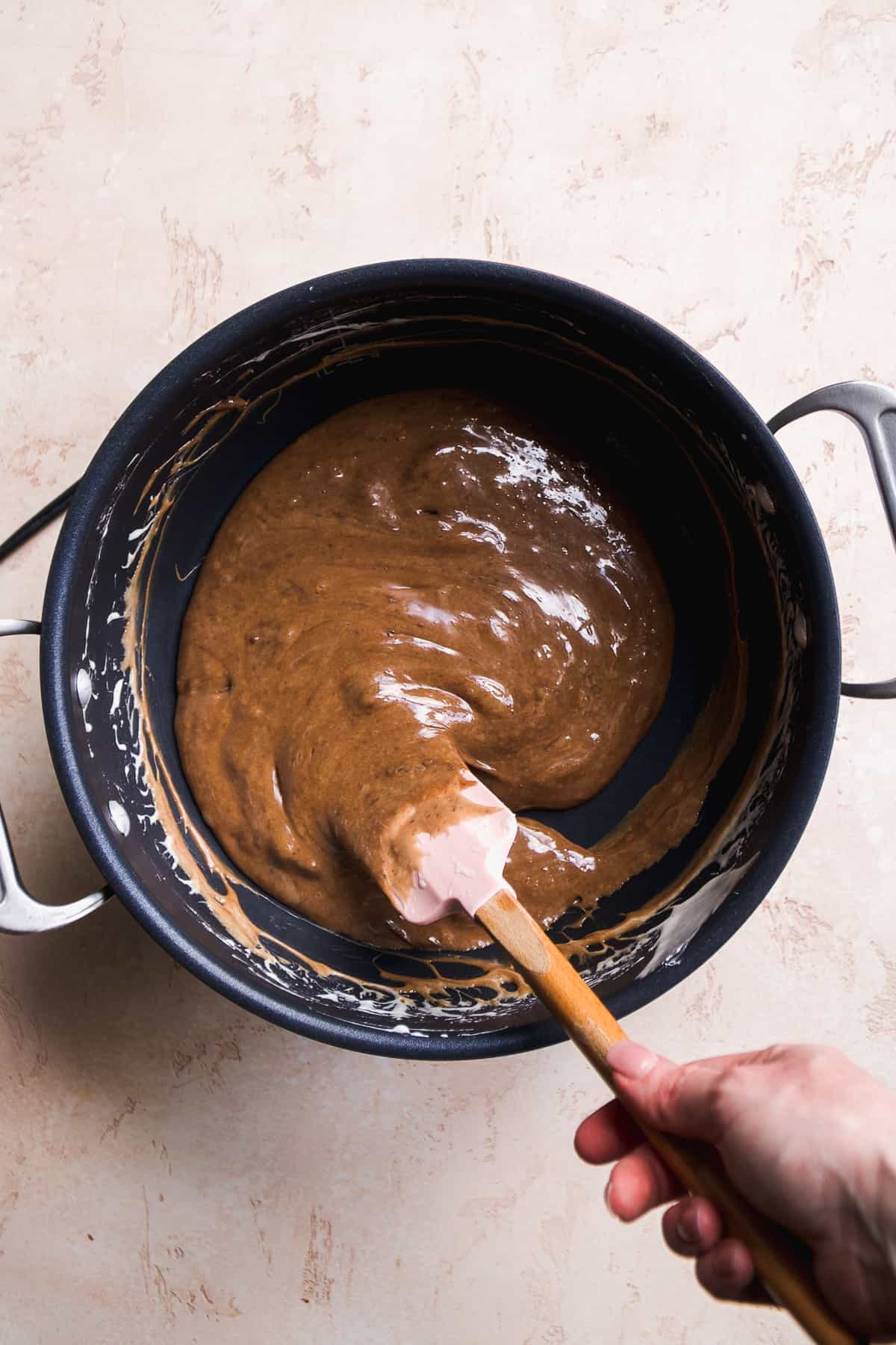Person mixing chocolate marshmallow fluff in a pot.