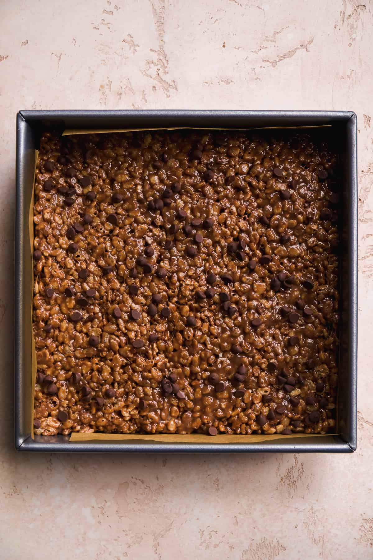 Square pan with chocolate rice krispies and chocolate chips on top.