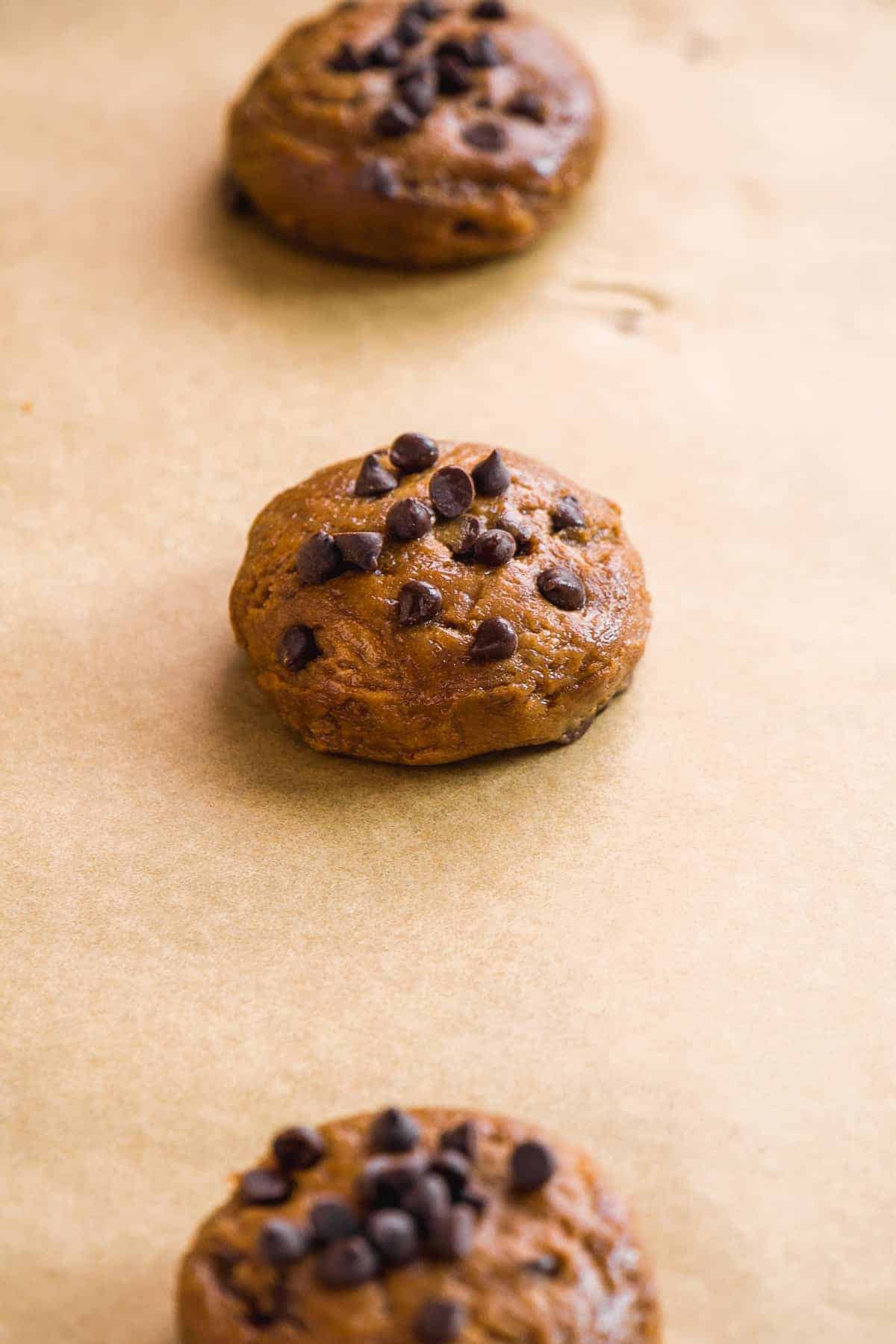 Peanut butter cookie dough with chocolate chips on a baking sheet about to be baked.