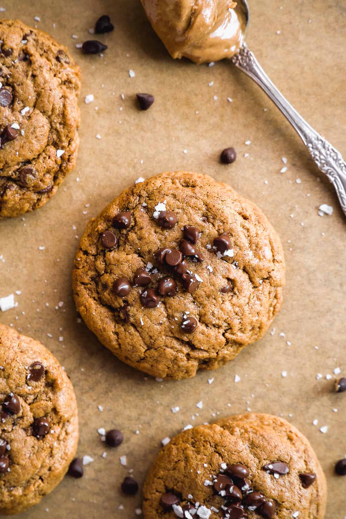 Peanut butter cookies on parchment paper with chocolate chips on top.