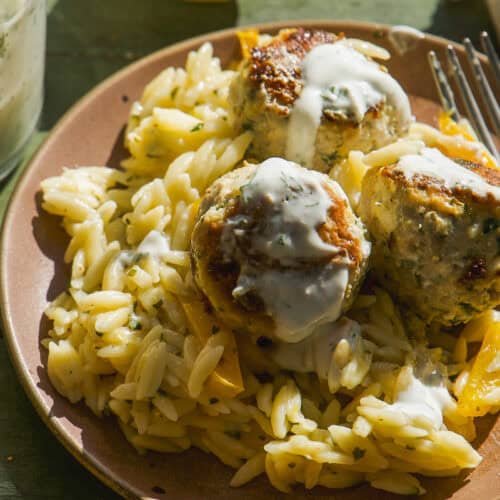 Greek chicken meatballs on a plate with lemon orzo.