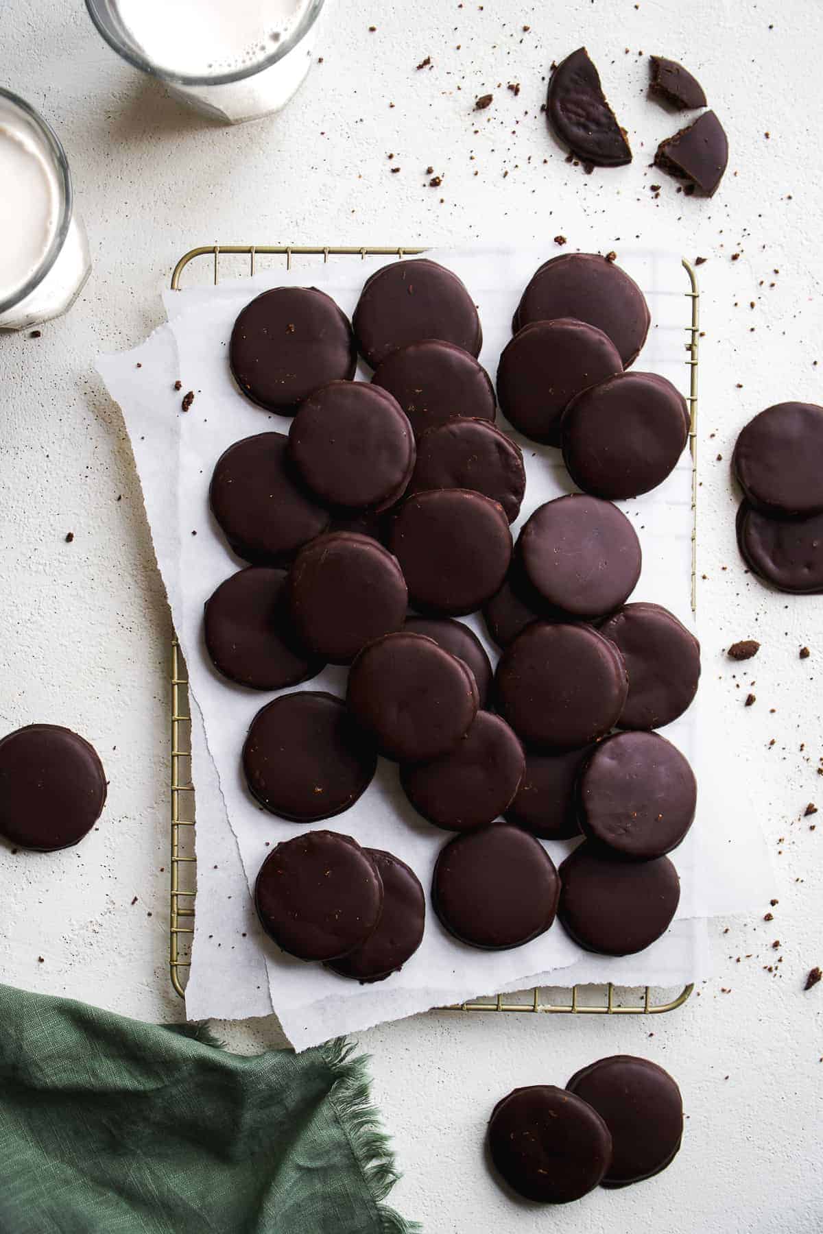 Vegan thin mints scattered on a wire rack with parchment paper.