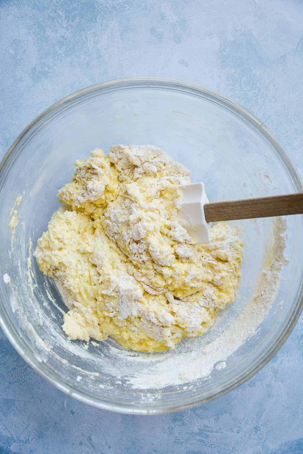 Overhead view of a clear mixing bowl with orange pound cake batter.