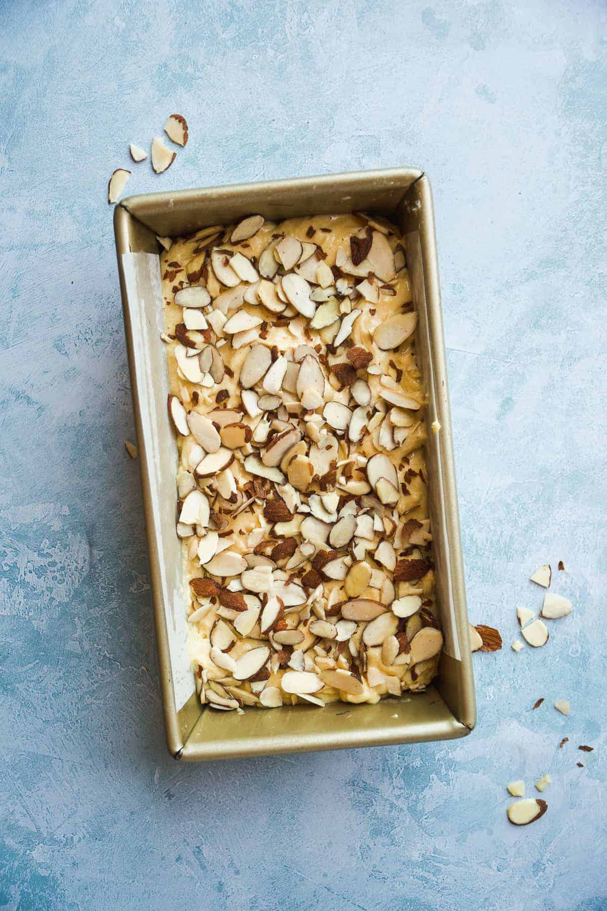 Overhead view of orange pound cake with almonds on top about to be baked.