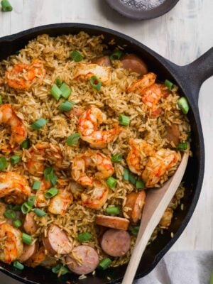 Skillet with cajun shrimp and rice on a white surface.