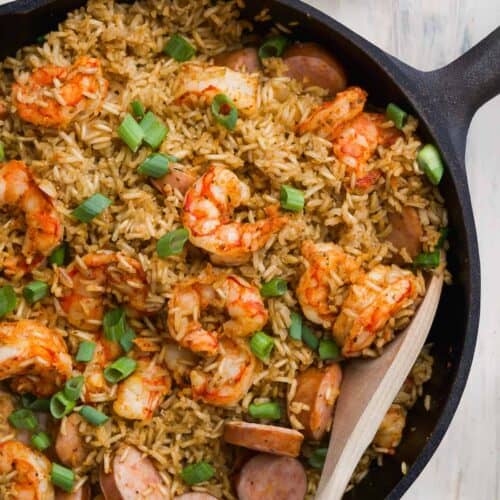 Skillet with cajun shrimp and rice on a white surface.