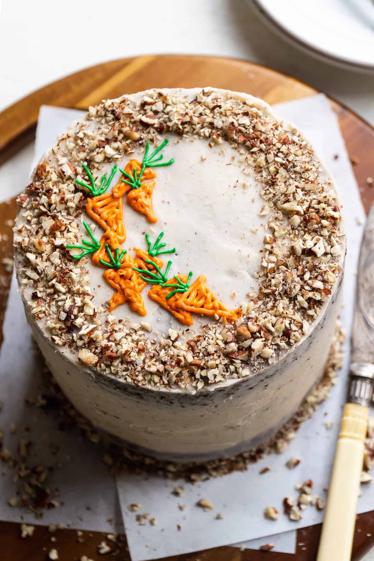 Chocolate carrot cake with carrots piped on top and pecans around the edges.