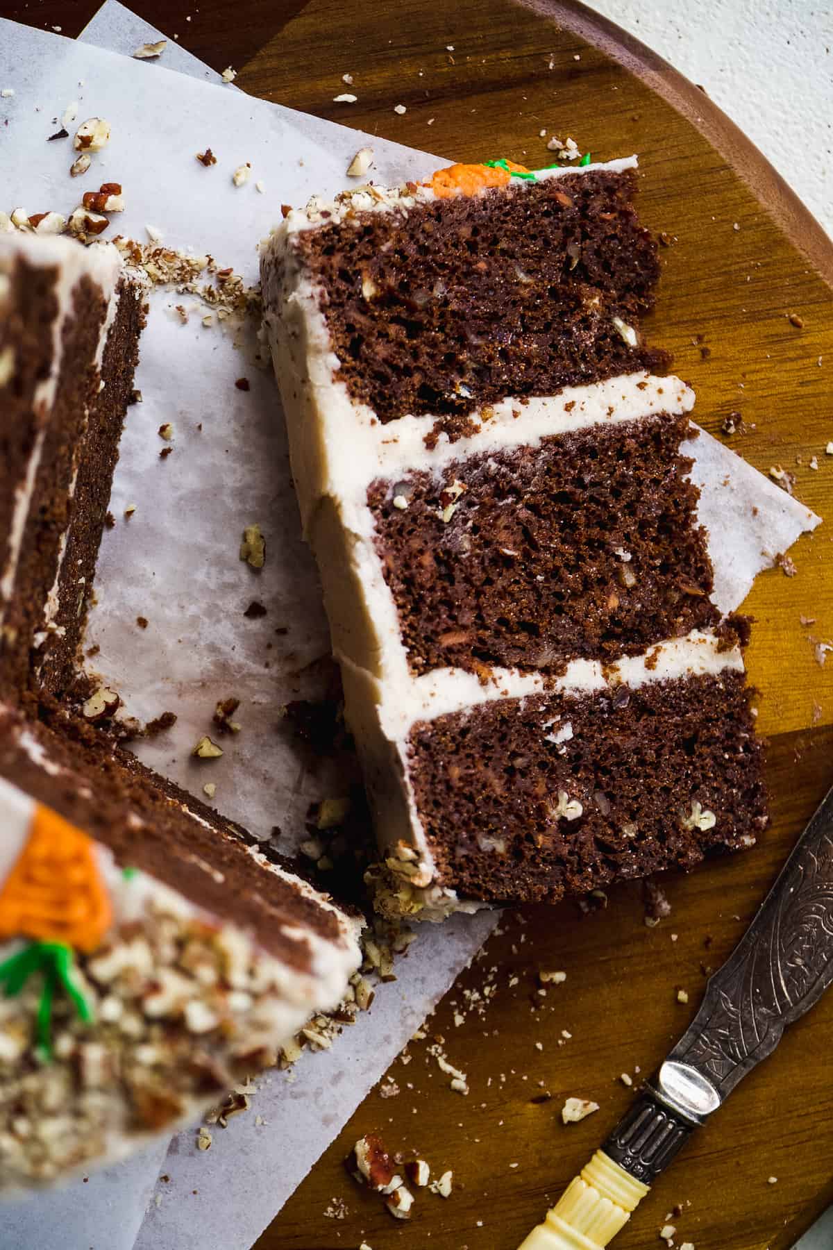 Overhead view of a slice of chocolate carrot cake on a wooden platter.