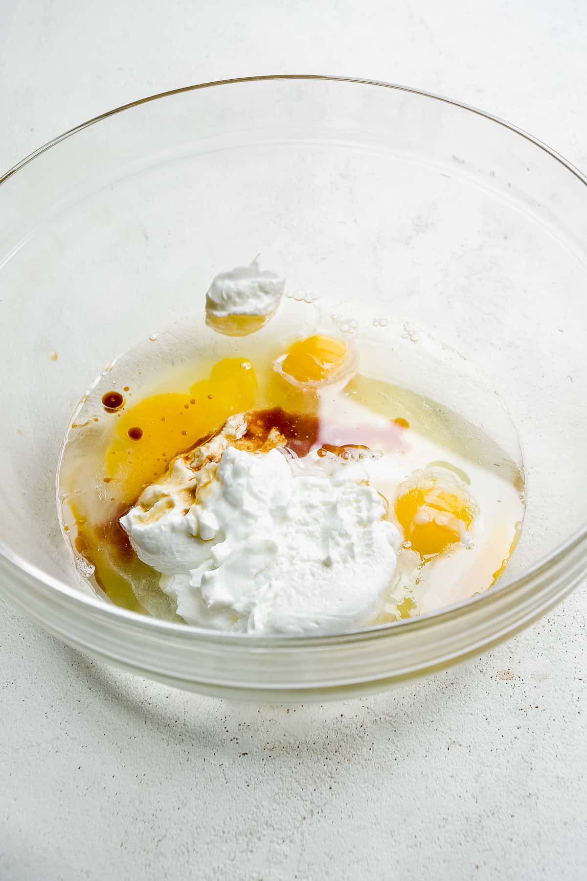 Clear bowl with wet cake ingredients about to be mixed.