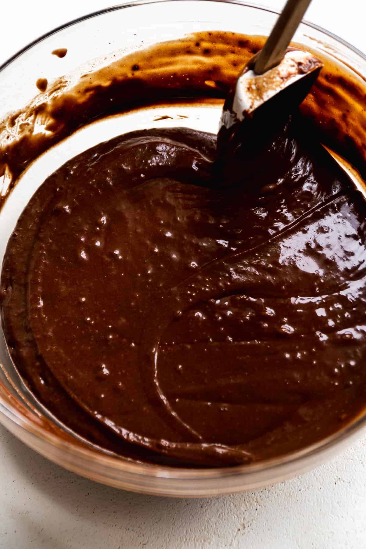 Chocolate carrot cake batter in a mixing bowl with a spatula.