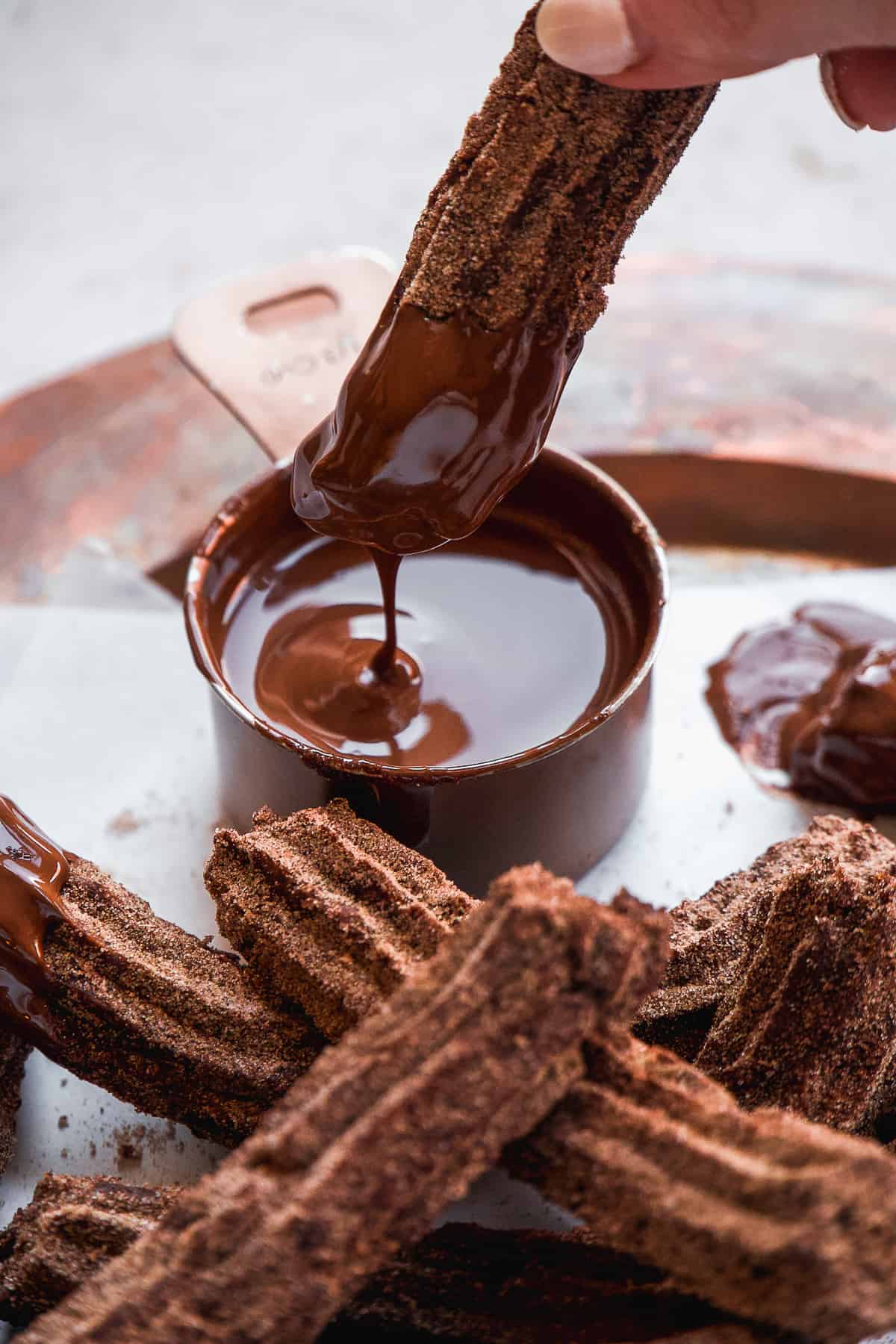 Person dipping a chocolate churro in a bowl of melted chocolate.