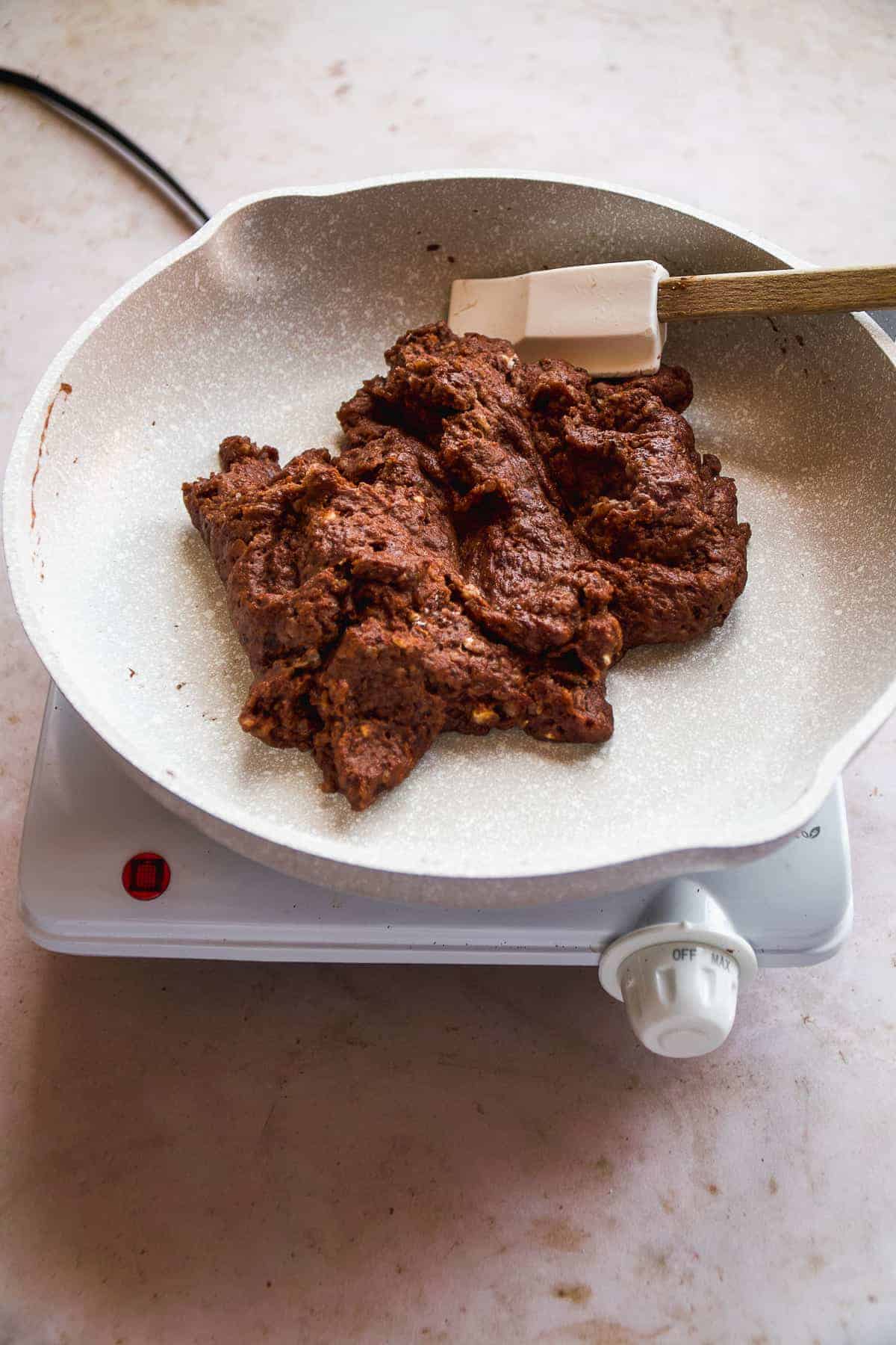 Chocolate dough in a gray skillet.