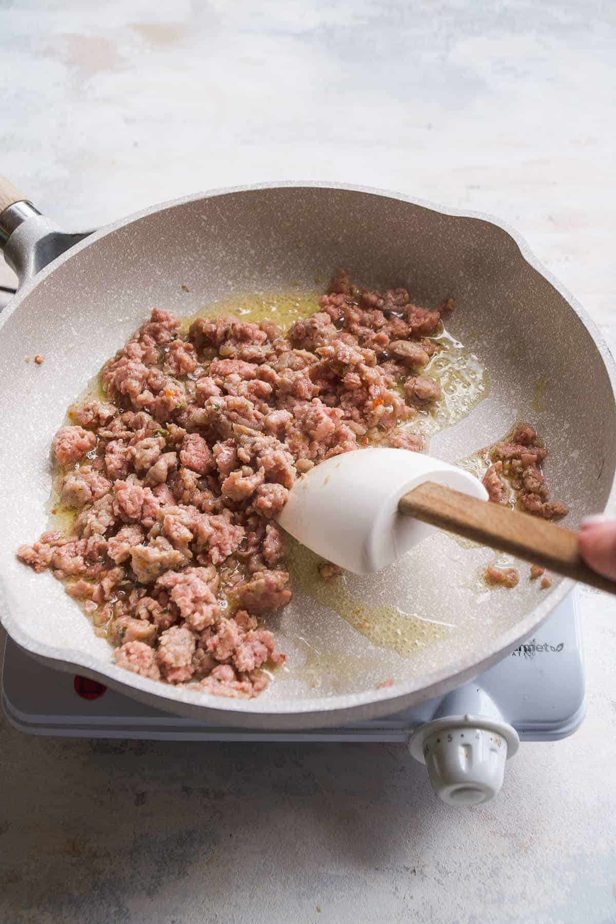 Breakfast sausage being cooked in a gray skillet.