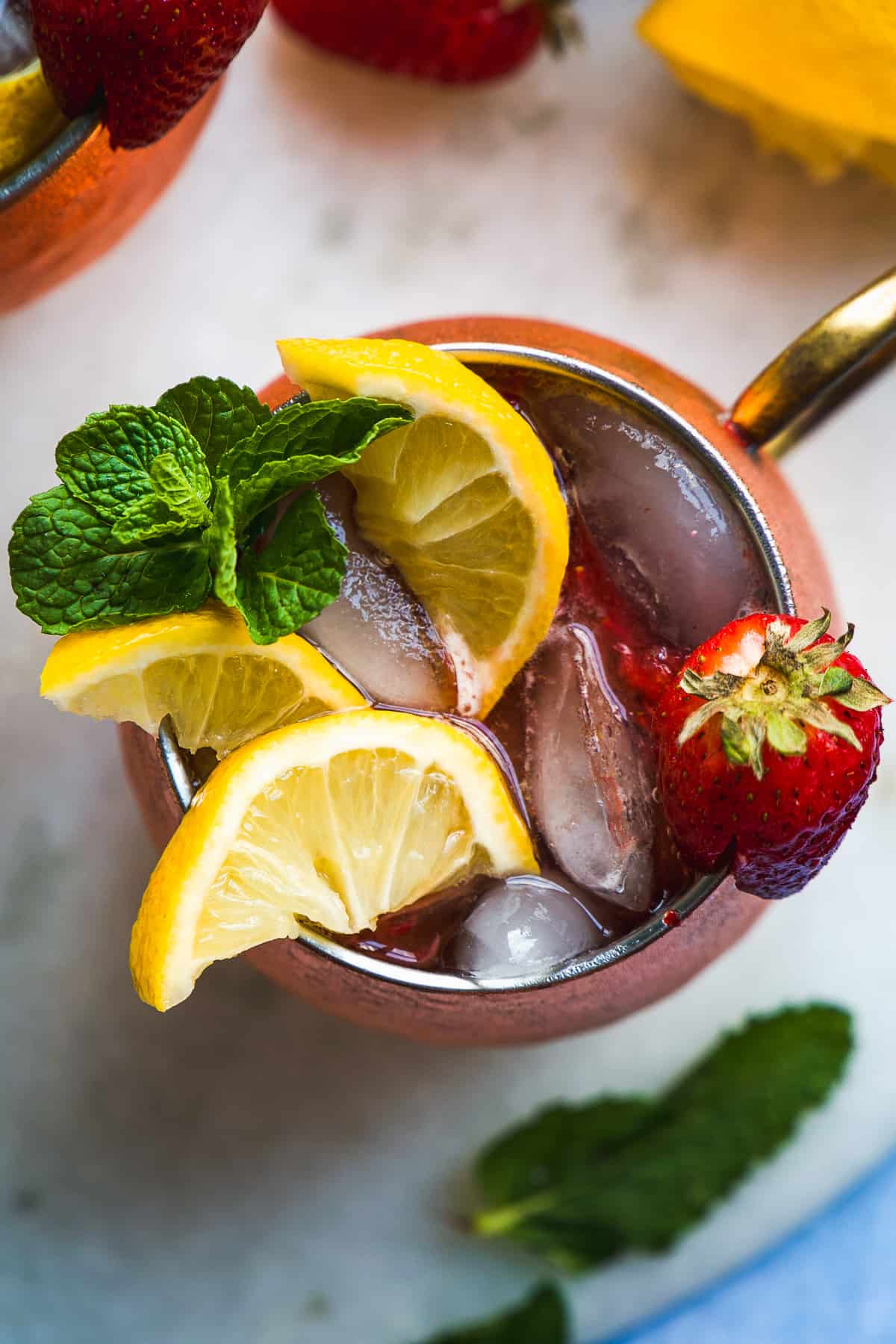 Overhead view of a Kentucky mule with strawberries and lemon slices on top.
