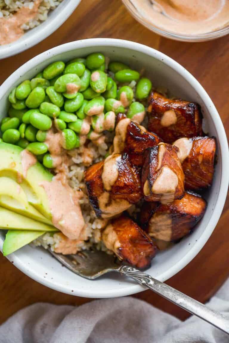 Air fried teriyaki salmon bites with edamame and avocado in a white bowl with a fork.