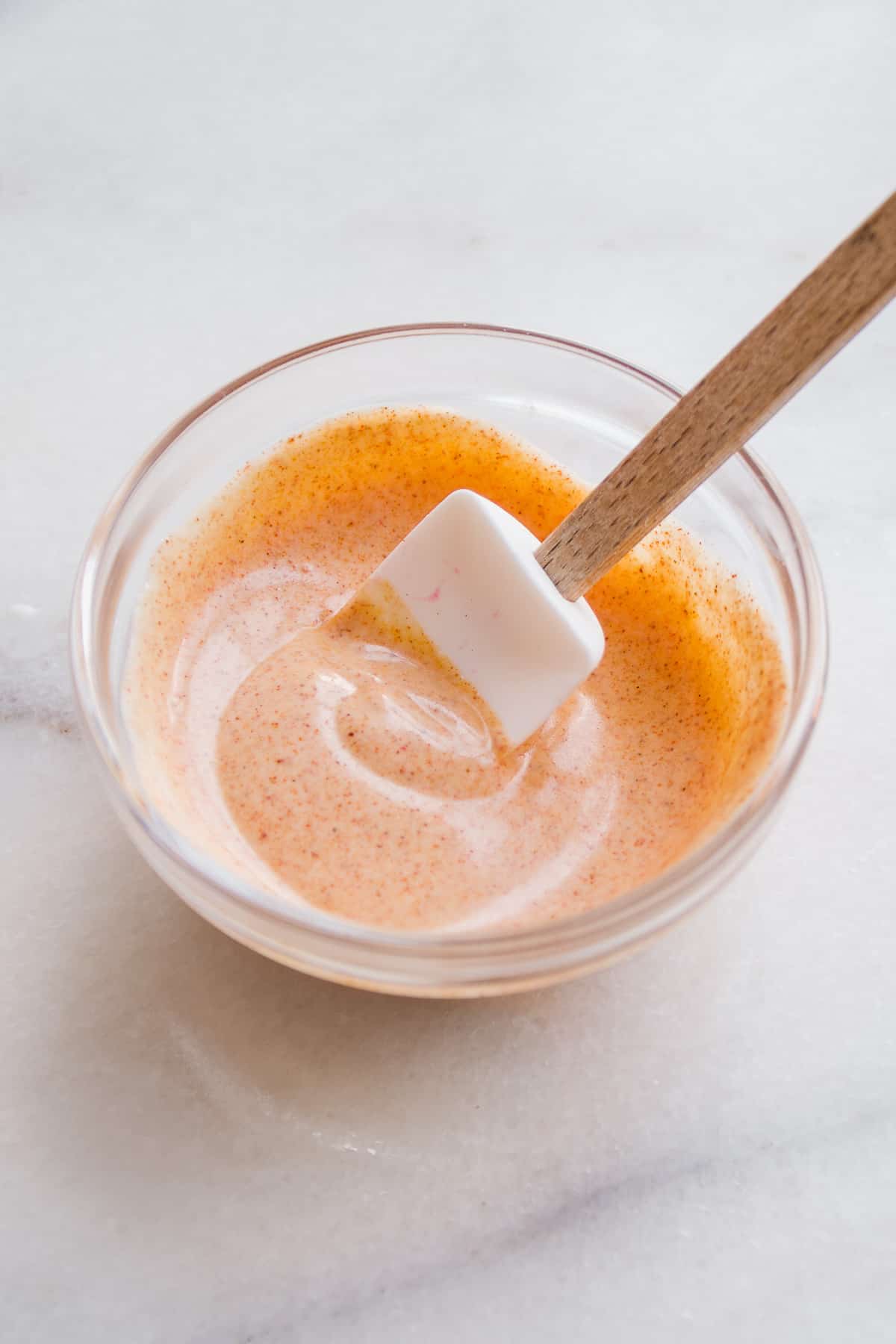Small bowl with orange spicy yogurt sauce.