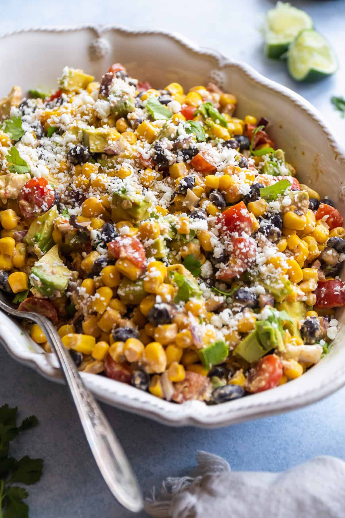 White serving dish with creamy corn salad and cheese on top.