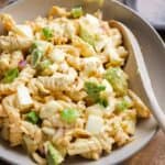 Deviled egg pasta salad in a bowl on a wooden surface.