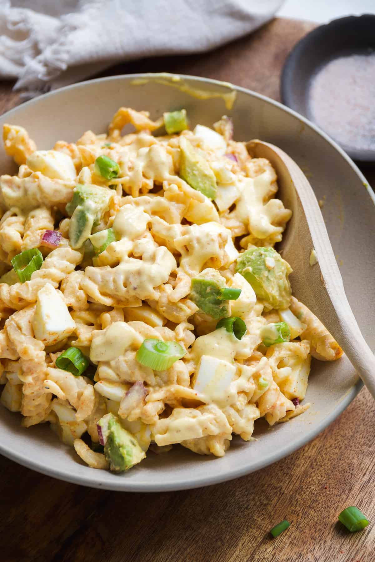 Deviled egg pasta salad in a bowl on wooden surface.