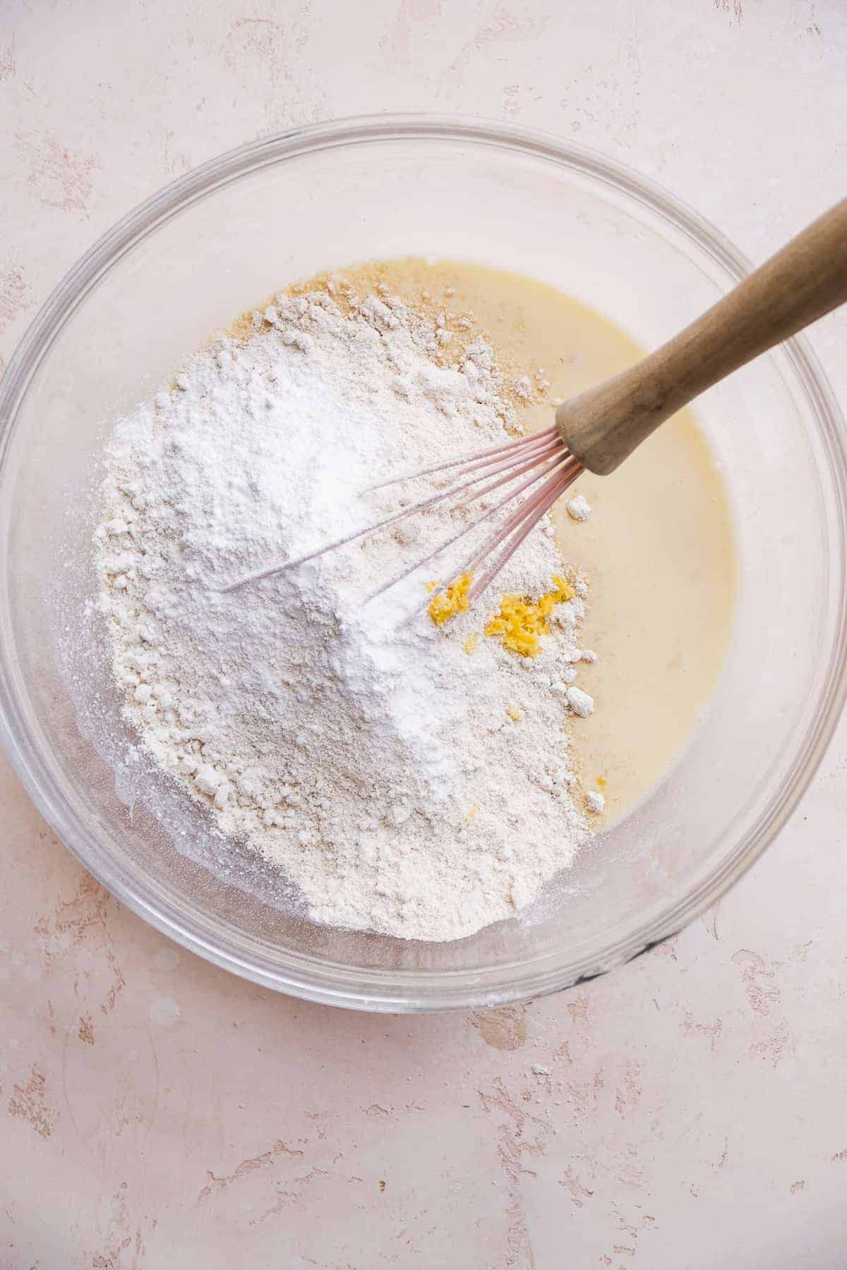 Dry ingredients about to be mixed into wet ingredients in a clear bowl.